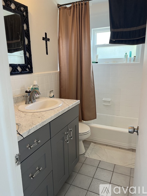 A bathroom with a sink, toilet, and a brown shower curtain.