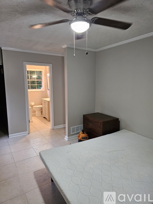 A bedroom with a bed, a ceiling fan, and a small wooden box on the floor.