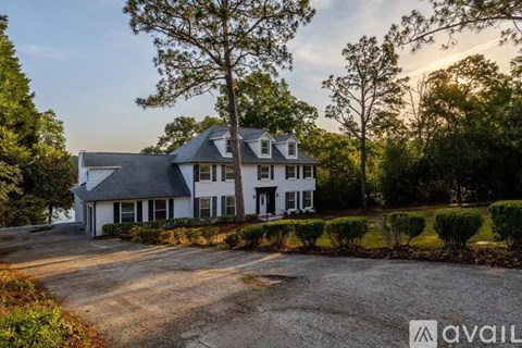 A large white house with a gravel driveway in front of it.