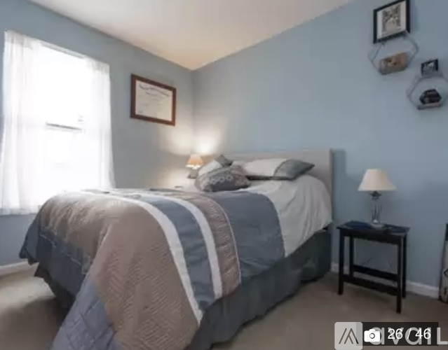 A bedroom with a bed, nightstand, and wall decor.
