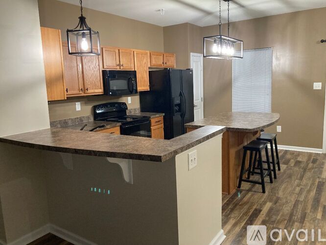 A kitchen with a black refrigerator and stove top oven.