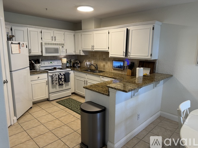 A kitchen with white cabinets and a granite countertop.