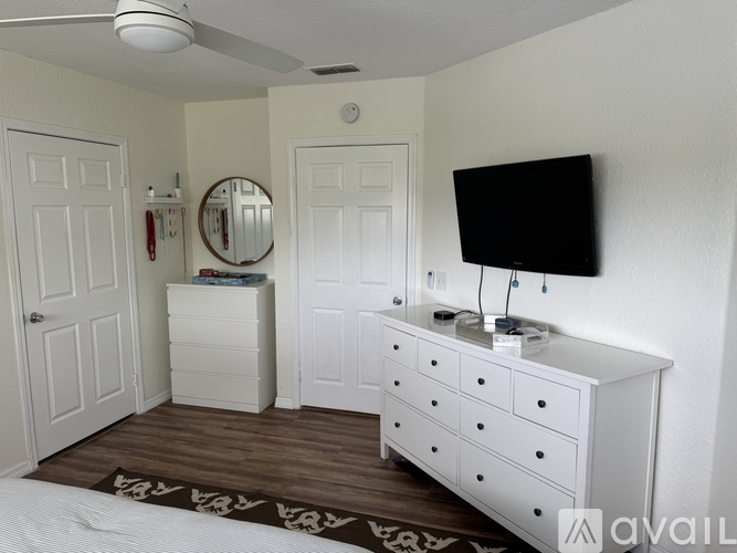 A white bedroom with a dresser and mirror.