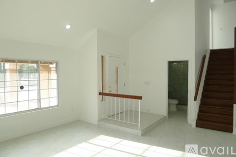 A spacious room with a staircase leading to another floor.