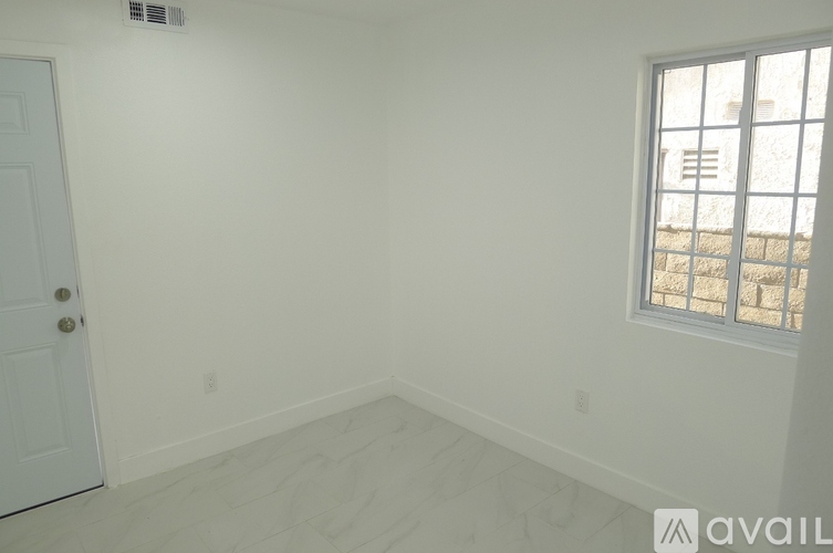 A room with a door and a window with a view of a building outside.