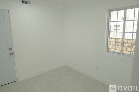 A room with a door and a window with a view of a building outside.