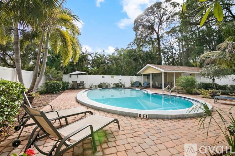 A small pool surrounded by a patio and trees.
