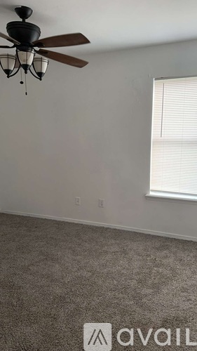 A room with a ceiling fan and a window with blinds.