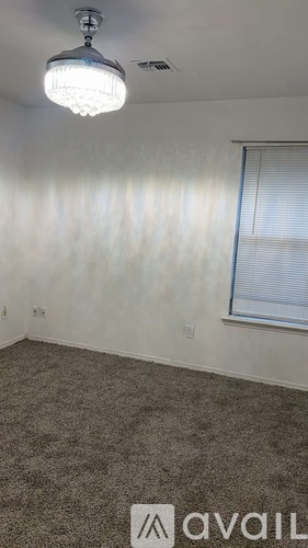 A room with a carpeted floor, a ceiling light, and a window with blinds.