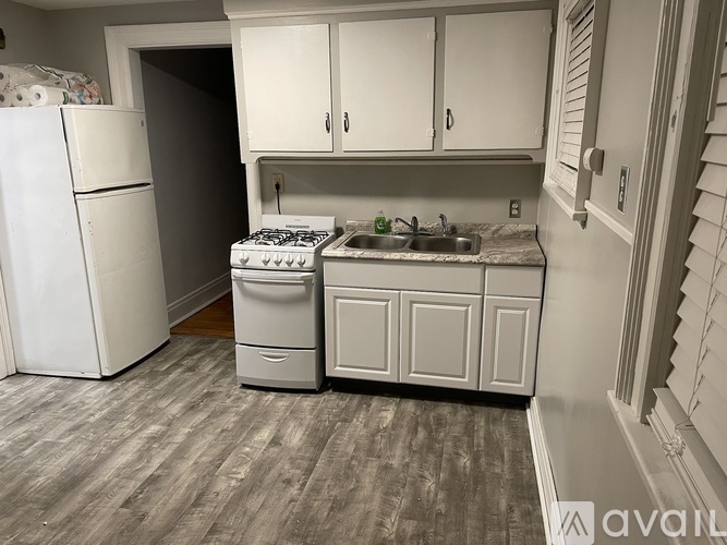 A kitchen with a white fridge, a white stove, and white cabinets.