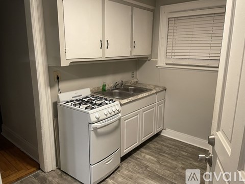 A white gas stove is in a kitchen with white cabinets.