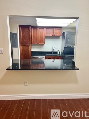 A kitchen with wooden cabinets and black countertops.