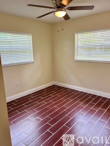 A room with a ceiling fan and two windows.