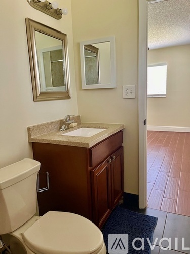 A bathroom with a toilet, sink, and mirror.