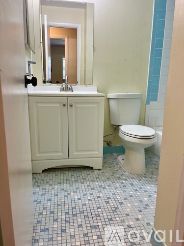 A white bathroom with a toilet, sink, and mirror.