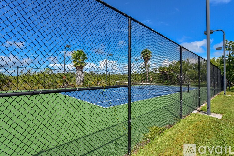 A tennis court is enclosed by a black fence.