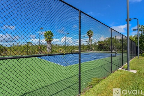 A tennis court is enclosed by a black fence.