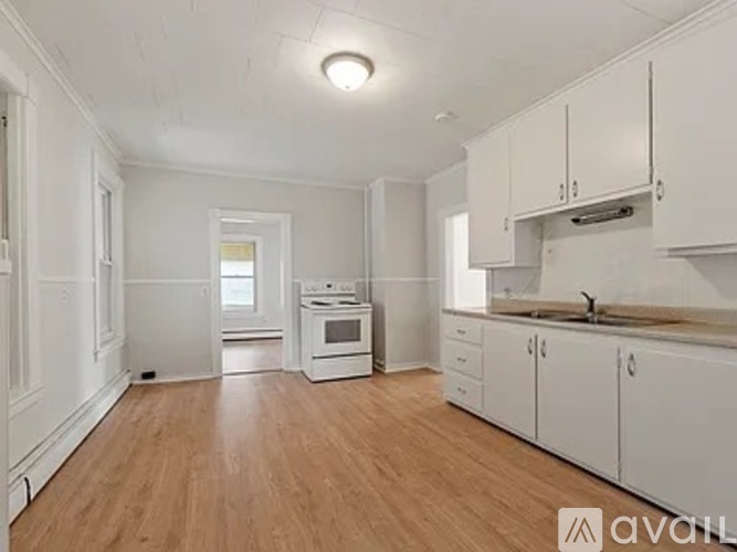 A kitchen with white cabinets and a wooden floor.