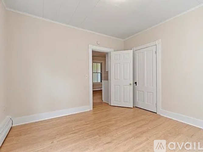 A room with wooden flooring and two white doors.