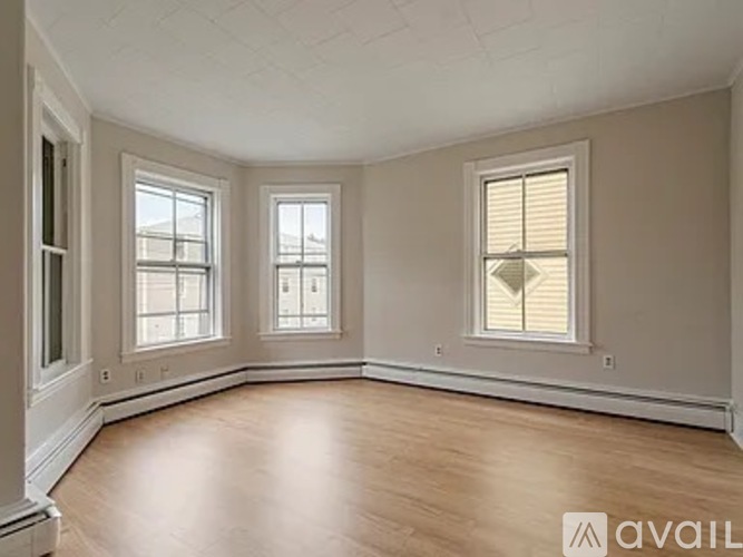 A room with wooden floors and three windows.