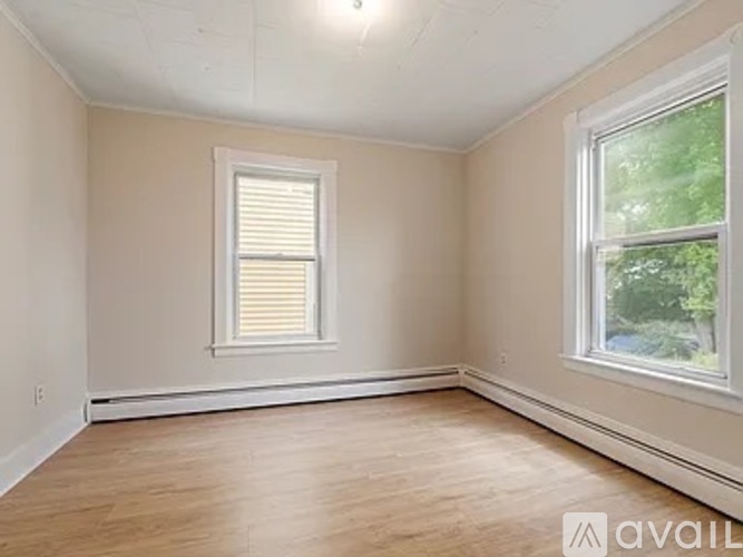 A room with a window and wooden flooring is available for rent.
