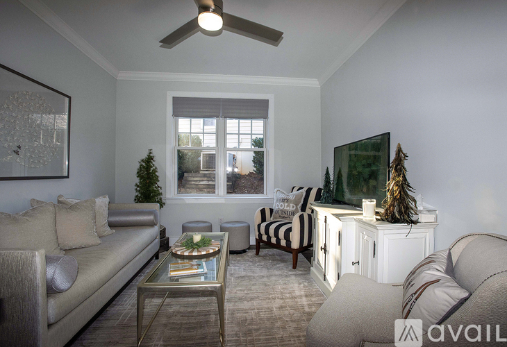 A living room with a grey couch, a glass coffee table, and a television on a cabinet.