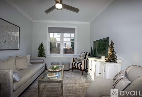 A living room with a grey couch, a glass coffee table, and a television on a cabinet.