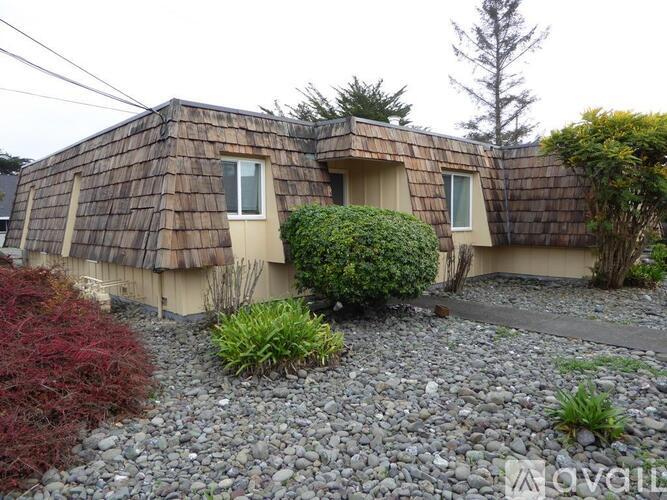 A house with a brown shingled roof and a gravel driveway.