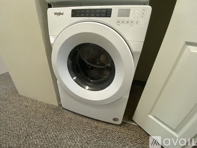 A white Whirlpool washing machine is placed in a room.