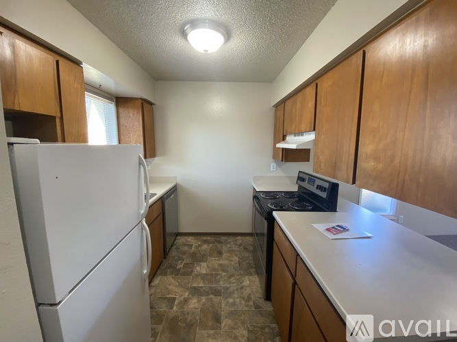 A kitchen with a white refrigerator, a stove, and wooden cabinets.