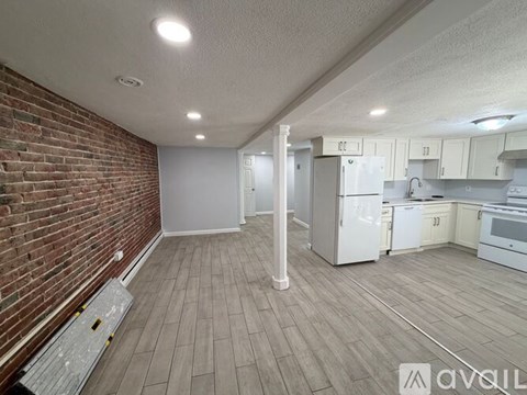 A kitchen with white appliances and a brick wall.