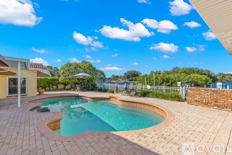 A swimming pool surrounded by a brick patio and a house.