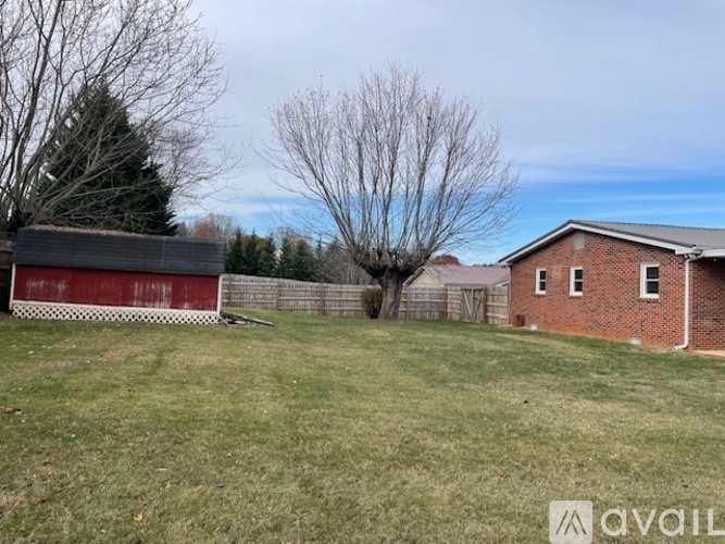 A red barn sits in a grassy field next to a brick house.