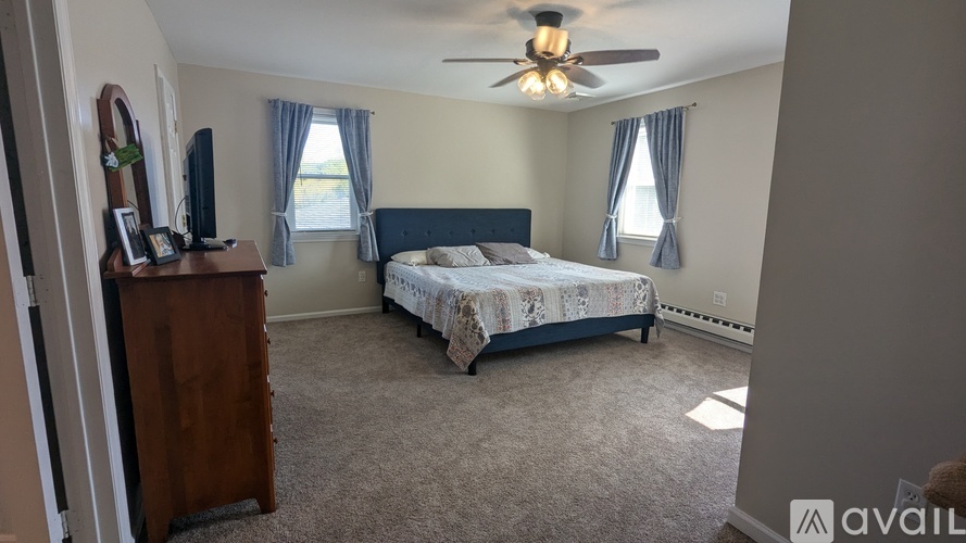 A bedroom with a bed, dresser, and a ceiling fan.