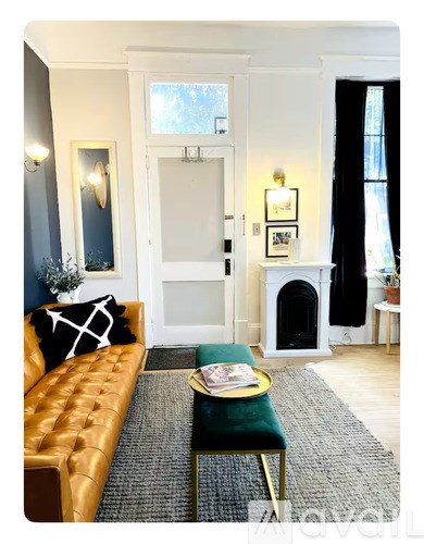 A living room with a gold couch and a green ottoman.