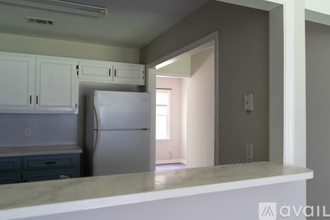 A kitchen with a white refrigerator and cabinets.