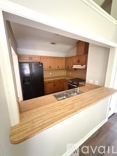 A kitchen with wooden cabinets and a black fridge.