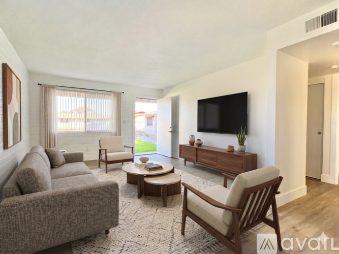 A living room with a grey couch, a wooden coffee table, and a flat screen TV mounted on the wall.