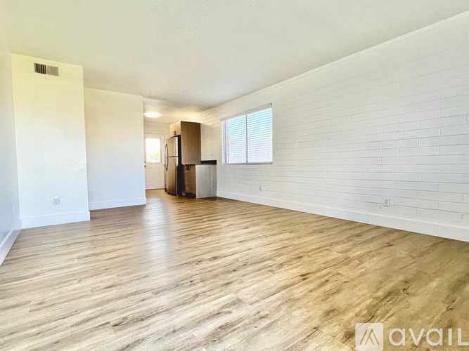 A spacious room with wooden flooring and white walls.