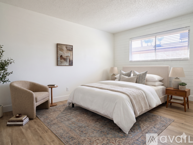 A bedroom with a large bed, a chair, and a small table.