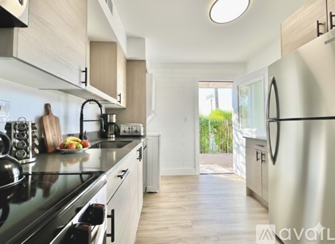 A kitchen with a black countertop and a refrigerator on the right.