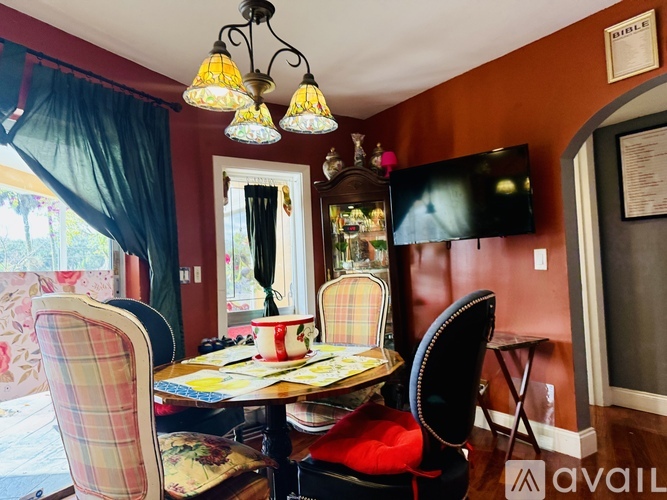 A dining room with a table set for four and a television mounted on the wall.
