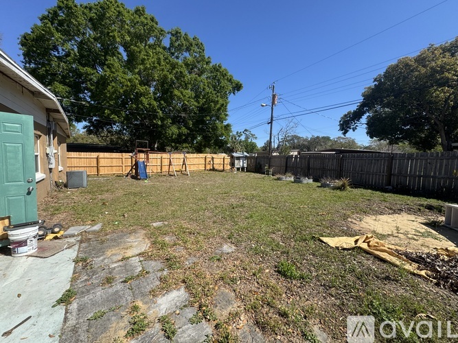 A backyard with a shed, a fence, and a tree.