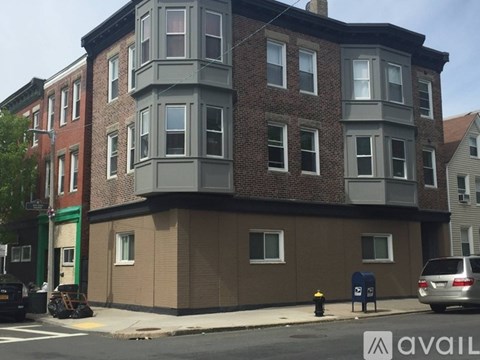 A building with a grey and brown facade is situated on a street corner.