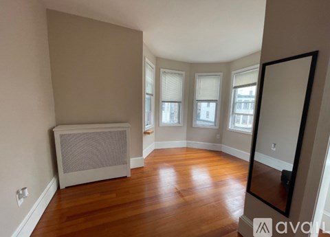 A spacious room with wooden floors and a large window.