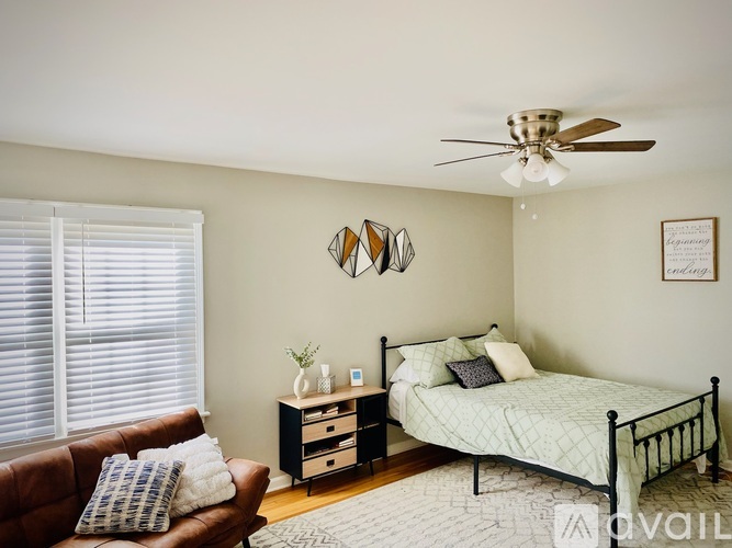 A bedroom with a bed, a couch, and a ceiling fan.