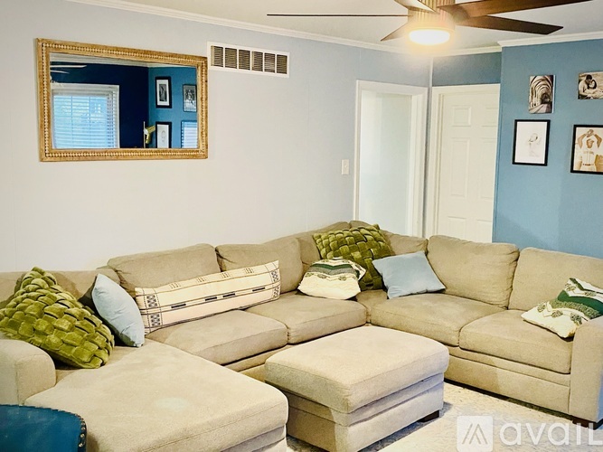 A living room with a beige couch and a mirror on the wall.