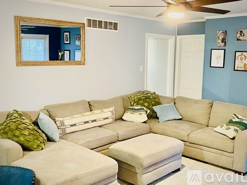 A living room with a beige couch and a mirror on the wall.