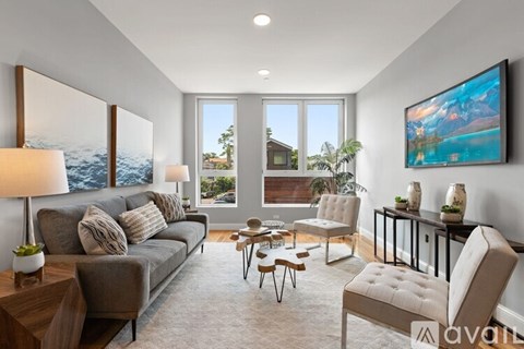 A living room with a grey couch, a brown armchair, a coffee table, and a painting on the wall.