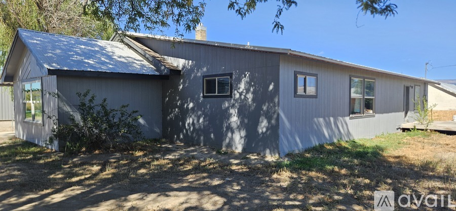 A house with a grey roof and a white wall is available for rent.